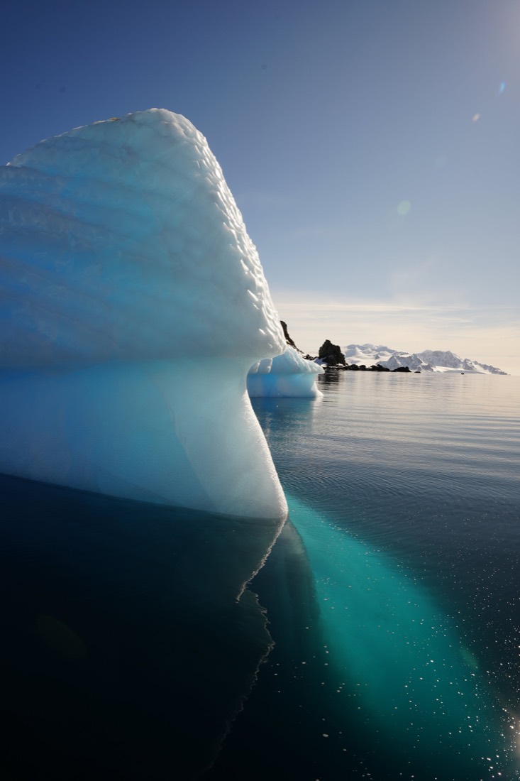 Blue iceberg with a glowing turquoise underwater keel in still Antarctic water