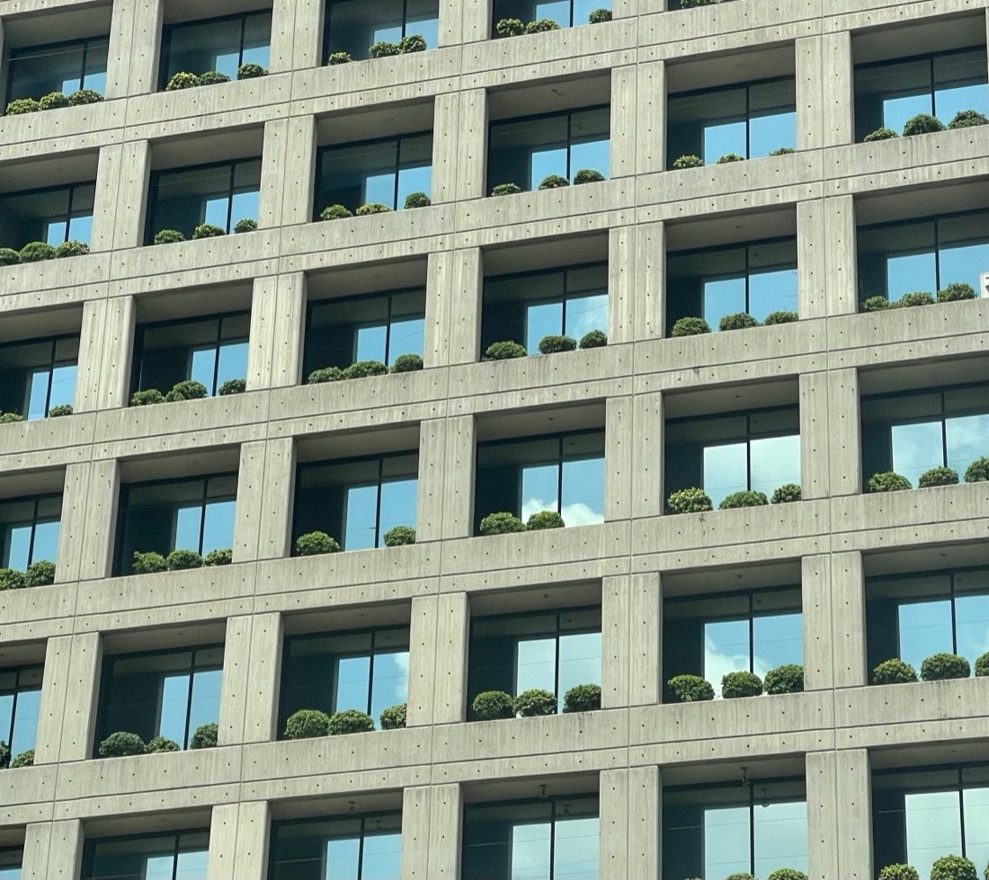 A concrete grid of balconies, each with a row of small green shrubs, on a building in Beirut