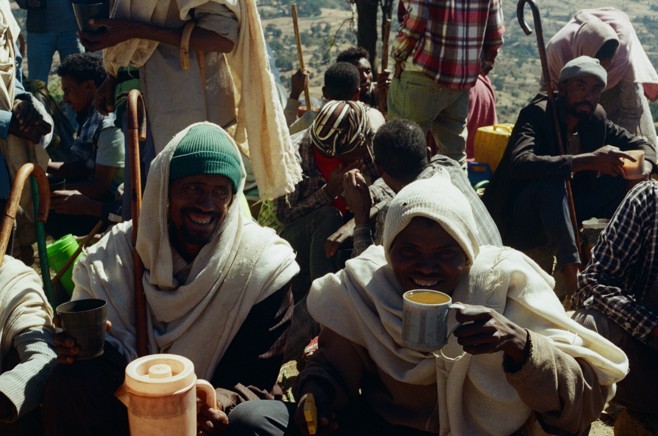 Highland men wrapped in white shawls share cups of tea at a gathering, on Fujifilm 400 film, Ethiopia