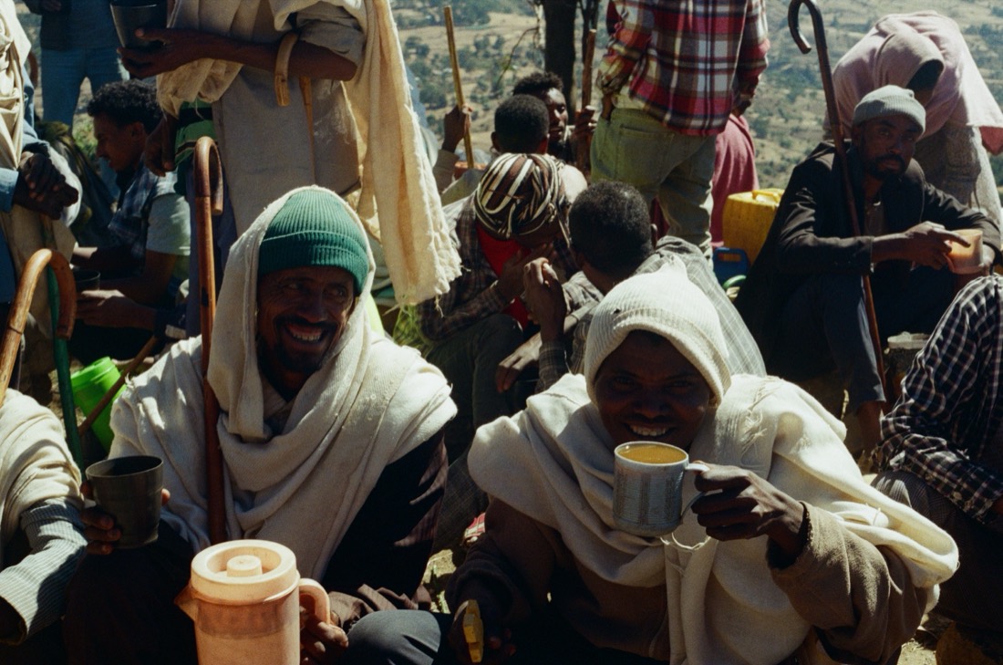 Highland men wrapped in white shawls share cups of tea at a gathering, on Fujifilm 400 film, Ethiopia