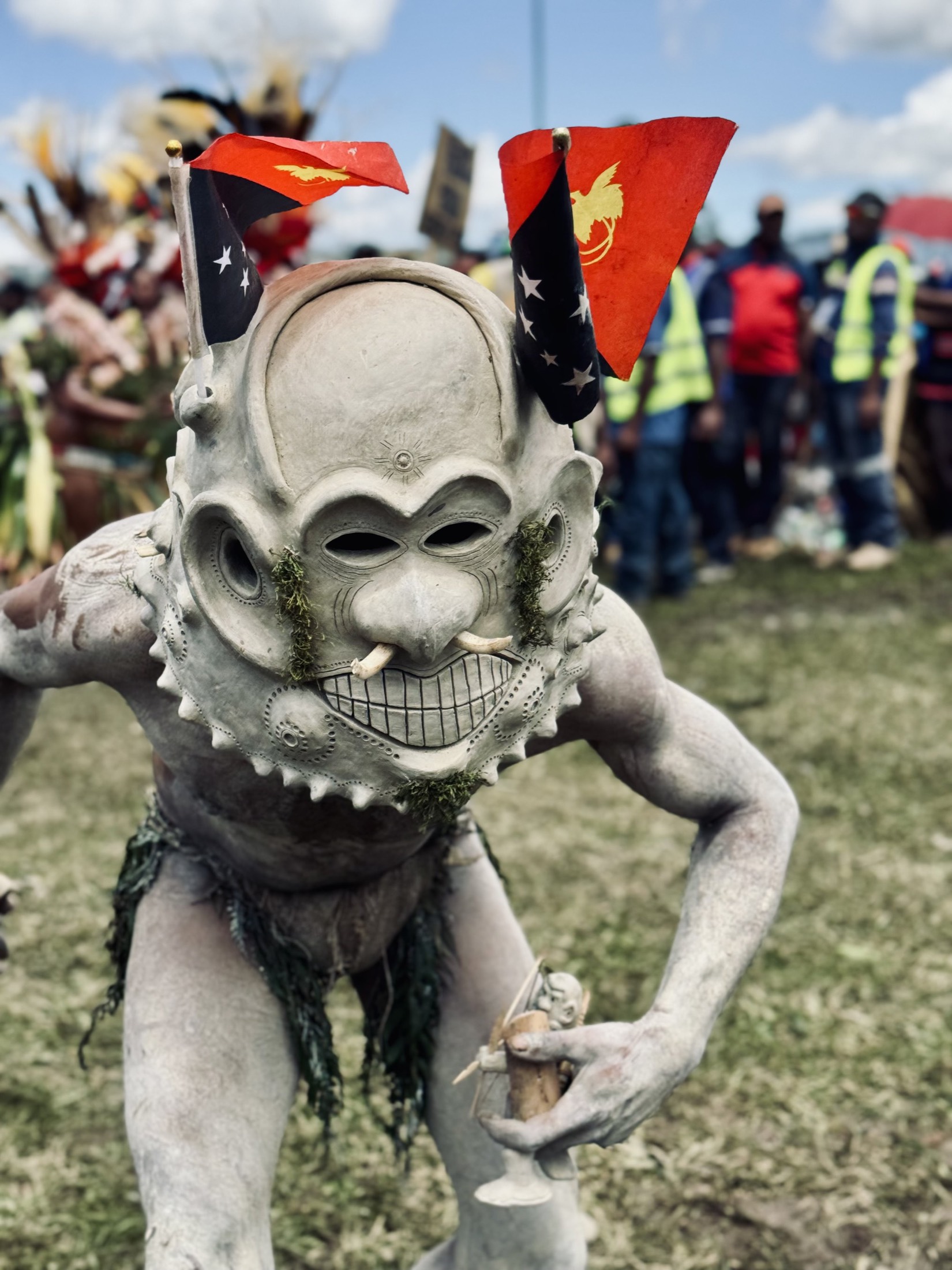 Performer in a carved skull mask and white body paint at a highland festival