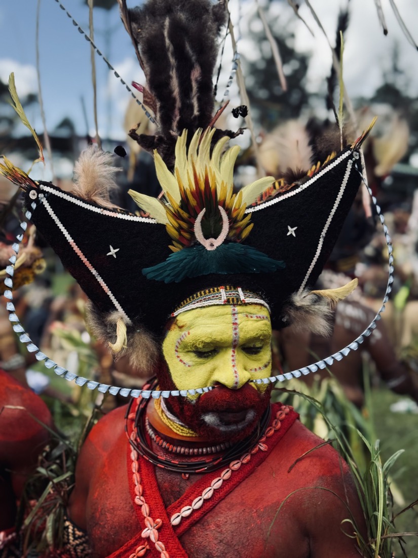 Man in a feathered headdress with yellow face paint at a highland festival