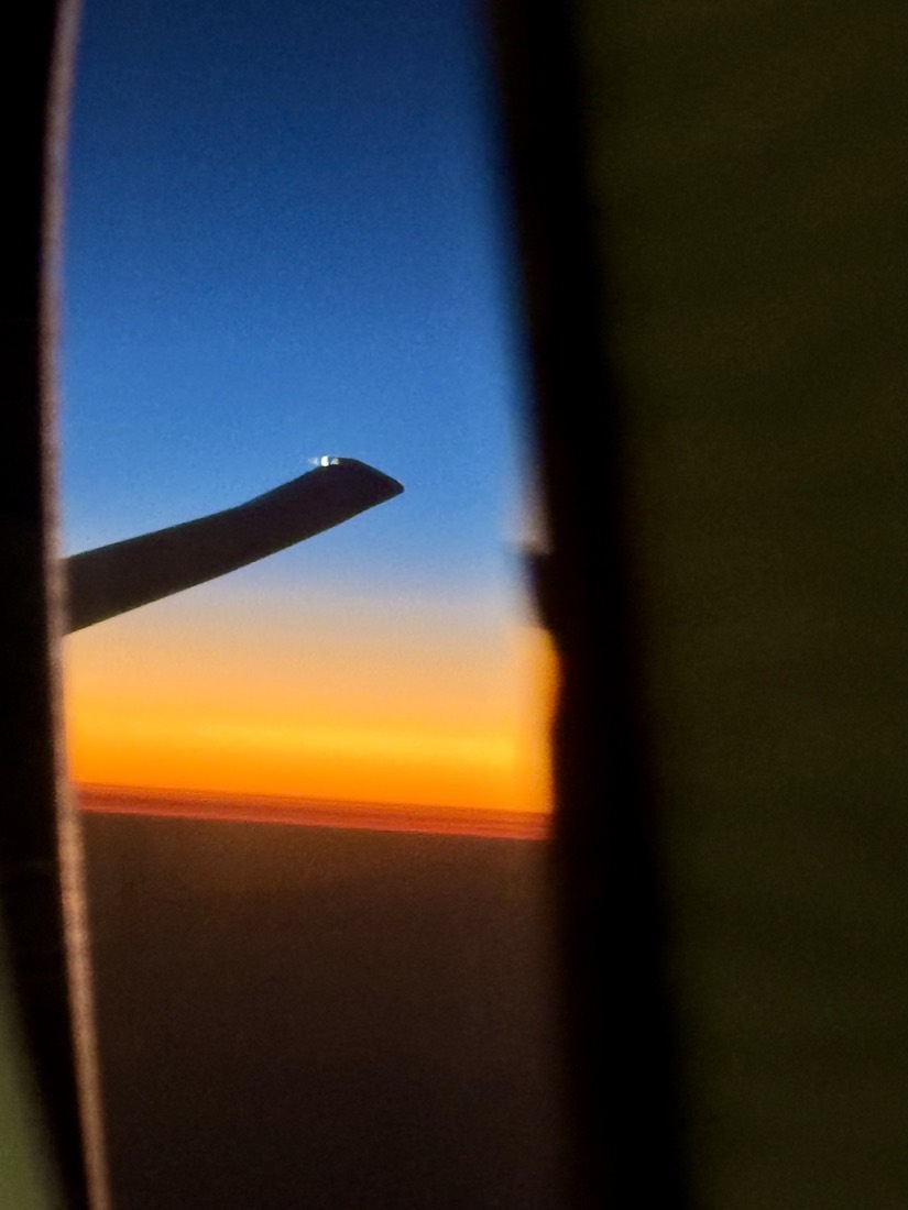 Aircraft window glowing with orange sunset light