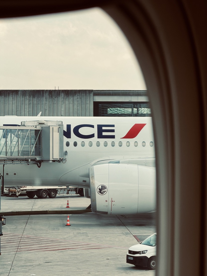 Air France airliner at the gate seen through a terminal window