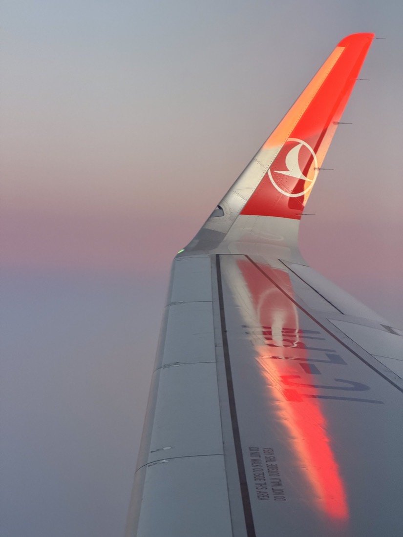Red wingtip of an airliner against a dusk sky
