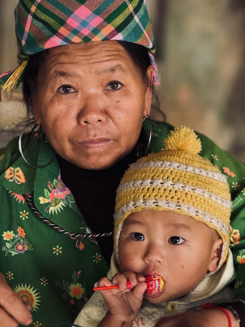 Grandmother in an embroidered headscarf holding a baby in a knitted hat