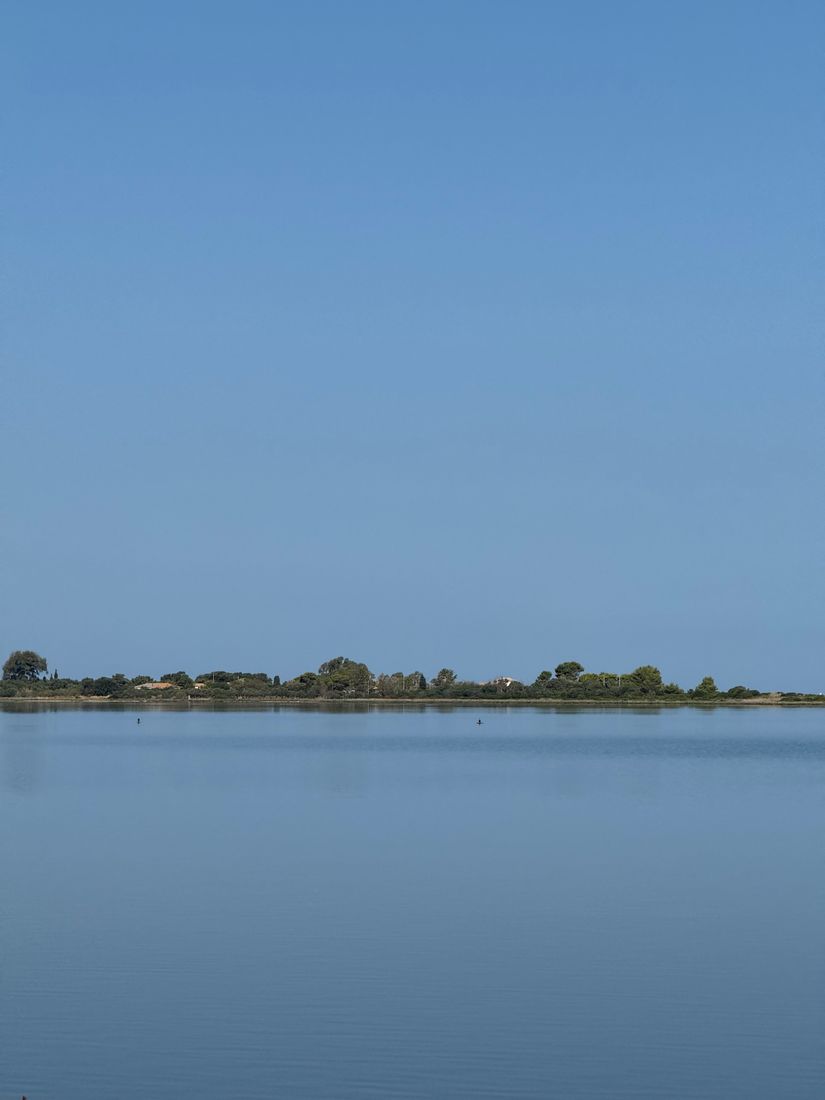 Calm pale-blue lagoon with a low line of trees on the far shore