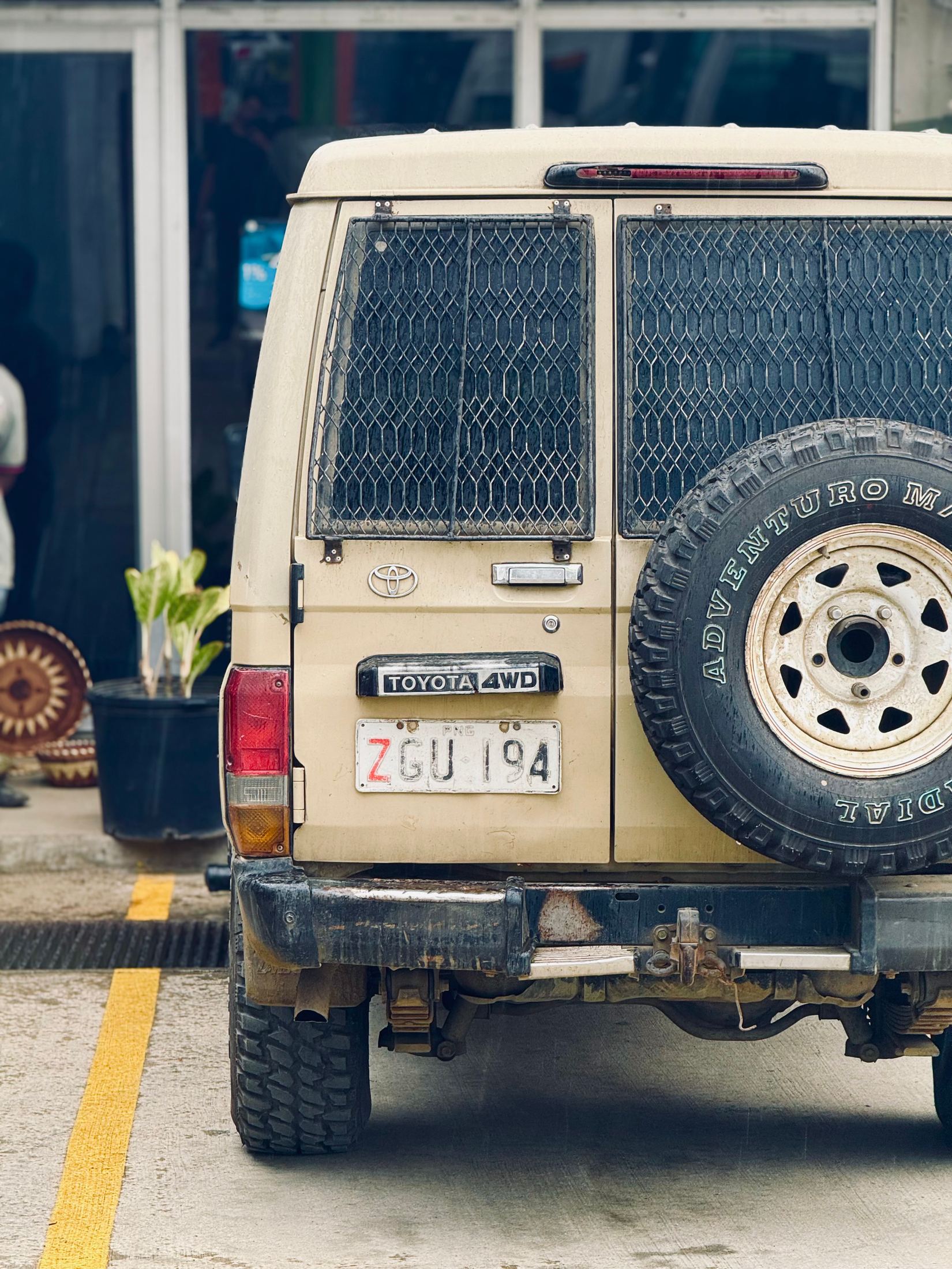 Rear of a sand-coloured Land Cruiser with a spare wheel and roof rack